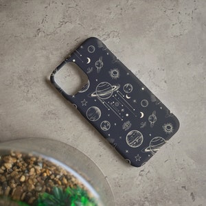 Peut inclure: Une coque de t&eacute;l&eacute;phone noire avec un motif c&eacute;leste blanc repr&eacute;sentant des plan&egrave;tes, des &eacute;toiles et des lunes.