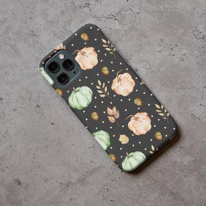 May include: A black phone case with a pattern of white dots, green and orange pumpkins, and brown leaves.