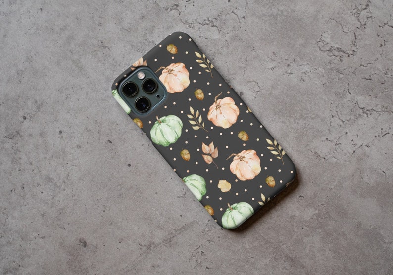 May include: A black phone case with a pattern of white dots, green and orange pumpkins, and brown leaves.