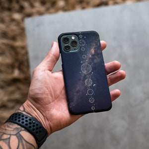 May include: A black phone case with a galaxy print and a white outline of the solar system.