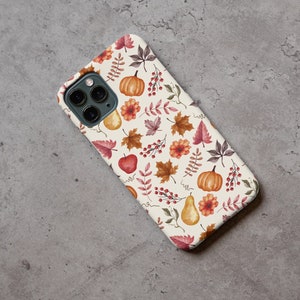 May include: A white iPhone case with a fall-themed design. The case features a pattern of red, orange, and yellow leaves, pumpkins, and pears.