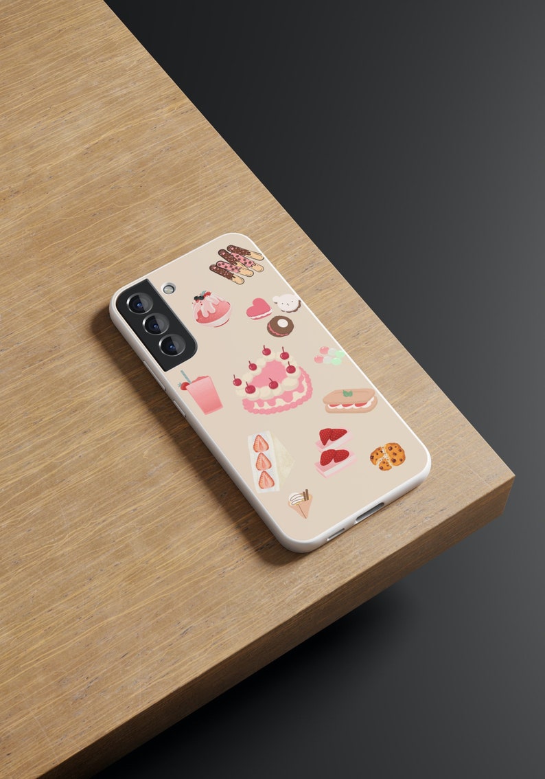 Peut inclure: Une coque de t&eacute;l&eacute;phone blanche avec une vari&eacute;t&eacute; d'autocollants de desserts roses et bruns, notamment des g&acirc;teaux, des biscuits et des glaces.