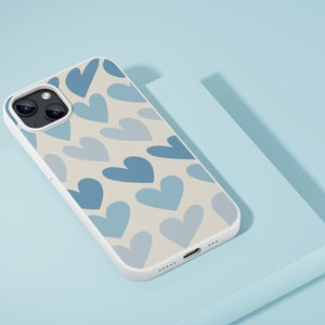 May include: A white phone case with a pattern of blue hearts on a cream background. The case has a camera lens cutout and a charging port.