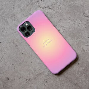 Pu&ograve; includere: Una custodia per telefono con sfumatura rosa e gialla con una scritta bianca che recita "progress not perfection".