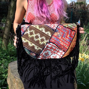 May include: A colourful patchwork bag with black fringe. The bag is made of different fabrics and has a variety of embroidery details.