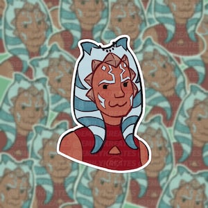 May include: A sticker featuring a cartoon illustration of Ahsoka Tano, a character from Star Wars. She is wearing her signature blue and white head-tails and a red top. Her face is painted with red and white markings.