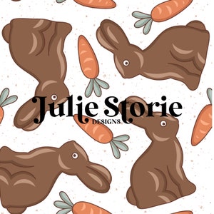 Peut inclure: Un motif sans couture représentant des lapins en chocolat brun et des carottes orange sur un fond blanc texturé. Le texte "Julie Storie Designs" est centré dans le motif.