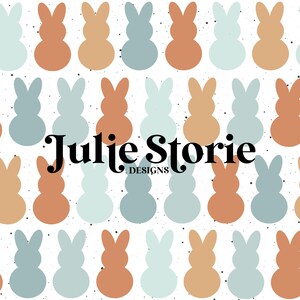 Peut inclure: Un fond blanc avec un motif répétitif de silhouettes de lapins bleu pastel et orange. Le texte "Julie Storie DESIGNS" est centré au milieu de l'image.
