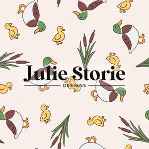 May include: A repeating pattern featuring cartoon ducks, ducklings, cattails, and reeds in shades of brown, green, and yellow on a light beige background. The text "Julie Storie DESIGNS" is centered.
