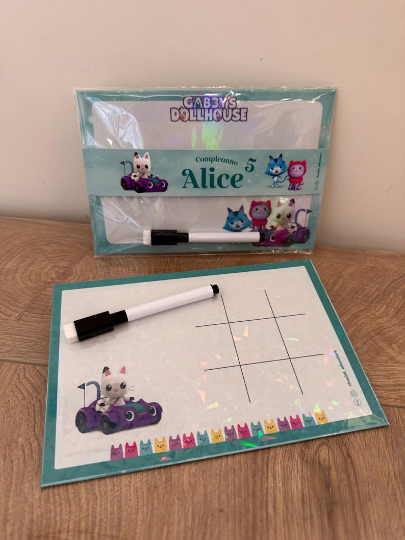 Puede incluir: Un set de pizarra blanca borrable con tem&aacute;tica de Gabby's Dollhouse que incluye un tablero con una cuadr&iacute;cula de tres en raya, un personaje en un coche morado y una fila de iconos de gatos de colores. Incluye un rotulador blanco borrable.