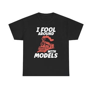 May include: Black t-shirt featuring the white text "I FOOL AROUND WITH MODELS". A red illustration of a train is below the text. The shirt is made of a soft material.