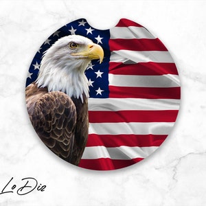 May include: A round coaster featuring a bald eagle with a white head and brown feathers, perched in front of a red, white, and blue American flag.