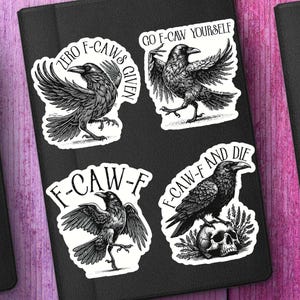 Puede incluir: Cuatro pegatinas de cuervos en blanco y negro con varias frases. Una dice "ZERO F-CAWS GIVEN", otra "GO F-CAW YOURSELF", una tercera "F-CAW-F" y la última "F-CAW-F AND DIE". Las pegatinas están sobre una superficie negra.