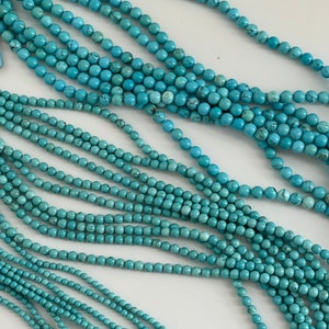 May include: A strand of turquoise blue beads, with multiple strands of beads layered on top of each other. The beads are round and smooth.