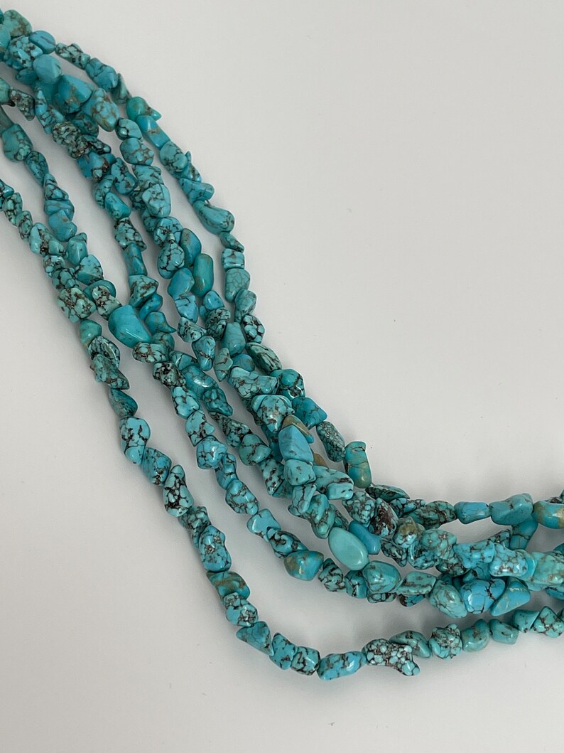May include: A strand of turquoise chip beads, featuring a light blue color with dark brown veining. The beads are irregular in shape and size, creating a natural and rustic look.