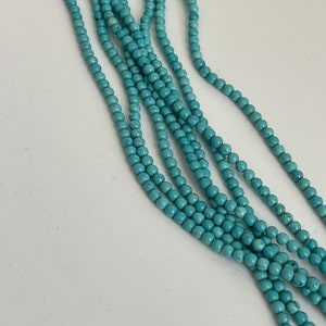 May include: A strand of turquoise blue beads, strung together in a long, multi-layered necklace.