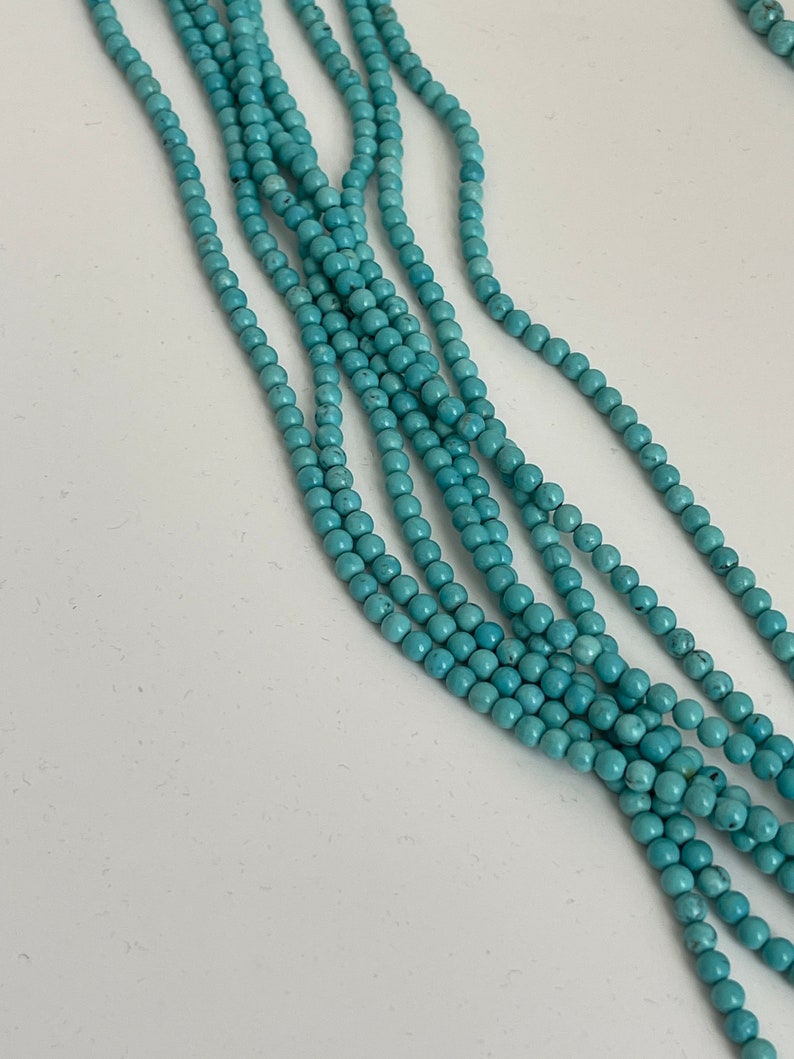 May include: A strand of turquoise blue beads, strung together in a long, multi-layered necklace.