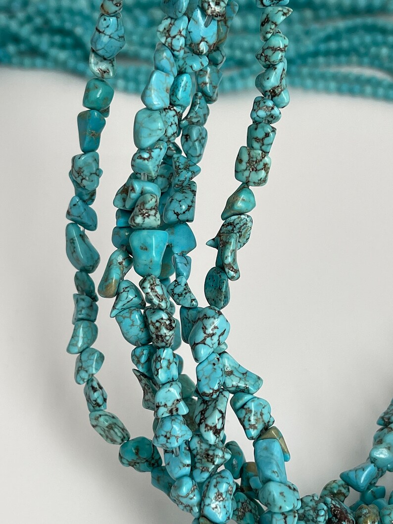 May include: A strand of turquoise chip beads, featuring a light blue color with dark brown veining. The beads are irregular in shape and size, creating a natural and rustic look.