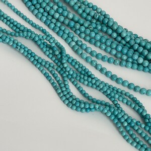 May include: A strand of turquoise beads, with multiple strands of beads layered on top of each other. The beads are a light blue color and have a smooth, round shape.
