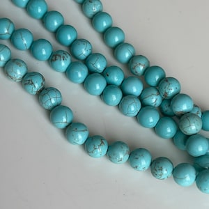 May include: A strand of turquoise blue beads with brown marbling. The beads are round and smooth.