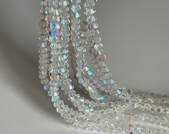 May include: A strand of clear iridescent crystal beads. The beads are small and have a faceted shape.