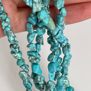 May include: A strand of turquoise chip beads, featuring a mix of light and dark blue hues with brown veining. The beads are irregular in shape and size, creating a natural and organic look.