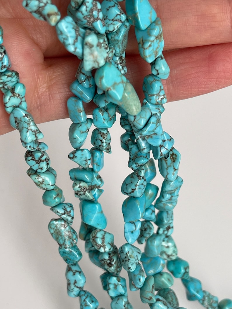 May include: A strand of turquoise chip beads, featuring a mix of light and dark blue hues with brown veining. The beads are irregular in shape and size, creating a natural and organic look.
