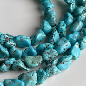 May include: A strand of turquoise gemstone beads, each bead is a unique, irregular shape with a light blue color and dark blue veining.