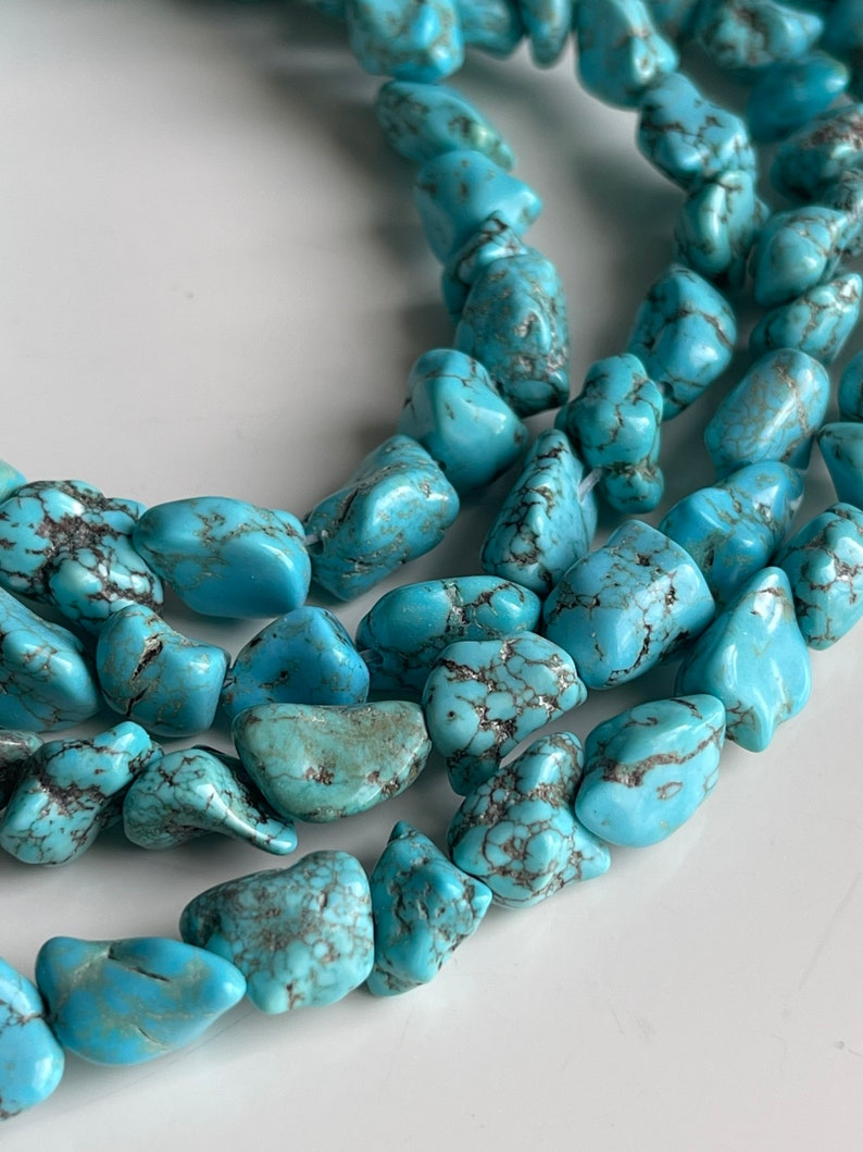 May include: A strand of turquoise gemstone beads, each bead is a unique, irregular shape with a light blue color and dark blue veining.
