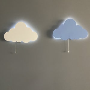 Peut inclure: Deux appliques murales en forme de nuage, l'une blanche et l'autre bleu clair, avec un cordon qui pend de chacune.
