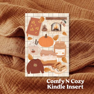 May include: A digital illustration of a cosy autumn scene with a fireplace, pumpkin, jumper, and a cup of hot chocolate. The text "Sweater Weather" is included in the image. The image is labelled "Comfy N Cozy Kindle Insert".