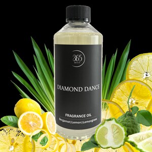 May include: A clear glass bottle with a black label that says "365 MIST" and "DIAMOND DANCE". The label also says "FRAGRANCE OIL" and lists the scents "Bergamot | Lemon | Lemongrass". The bottle is surrounded by lemons and lemongrass.