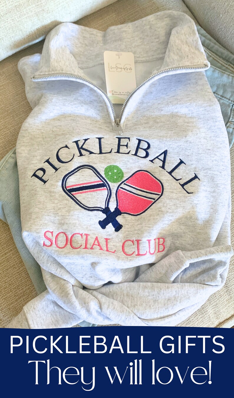 May include: Gray sweatshirt with a navy blue embroidered design that says "Pickleball Social Club" with two crossed pickleball paddles and a green ball.