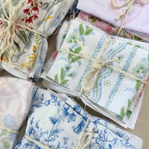 Puede incluir: Conjunto de paquetes de tela atados con cuerda. Las telas presentan estampados florales y bot&aacute;nicos en varios colores, incluyendo rojo, amarillo, azul y rosa. Algunos paquetes tienen dise&ntilde;os de lazo.