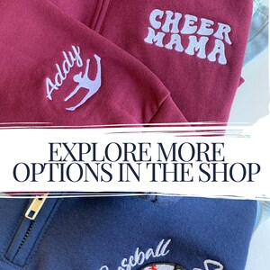 May include: Two zippered sweatshirts with embroidered designs. The first sweatshirt is maroon with "Cheer Mama" and a stylized figure on the front. The second sweatshirt is navy blue with a baseball and softball design and the text "Baseball Softball Mom" on the front.