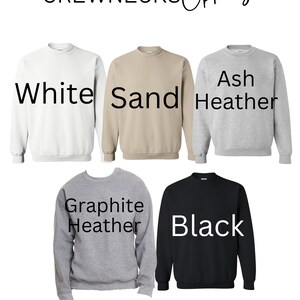 May include: Five crewneck sweatshirts in different colors: white, sand, ash heather, graphite heather, and black.  The sweatshirts are laid out flat on a white background.