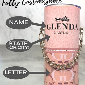 May include: A pink tumbler with a silver chain handle. The tumbler has a white stitched line around the top and a pattern of pink and brown letters. The tumbler is personalised with the name "GLENDA" and the state "MARYLAND".