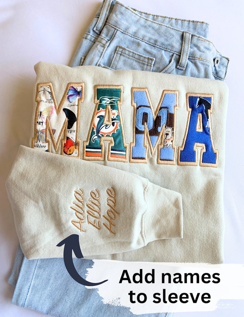 May include: A beige sweatshirt with the word "MAMA" spelled out in colorful fabric patches. The sweatshirt has a sleeve with the names "Addie, Ellie, Hope" embroidered on it.