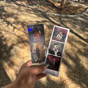 May include: Two tickets are held in a hand. One ticket reads "Cosa Nuestra World Tour" with a cityscape graphic. The other ticket has three photo booth-style images of a man. The tickets are rectangular with rounded corners.