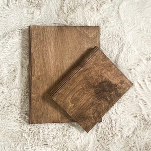 Peut inclure: Deux planches en bois, l'une empilée sur l'autre, toutes deux avec une teinture brun foncé. Les planches sont sur une surface blanche et moelleuse.