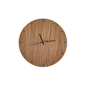 Könnte beinhalten: Eine runde Holzuhr mit schwarzen Zeigern und schwarzen Stundenmarkierungen. Das Zifferblatt der Uhr ist aus hellbraunem Holz mit einer Holzmaserung.