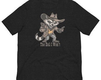 Puede incluir: Camiseta gris oscuro con un mapache de dibujos animados con sombrero de vaquero y dos pistolas. El mapache lleva una chaqueta color canela y pantalones grises. El texto "The Hell I Won't" está impreso debajo.