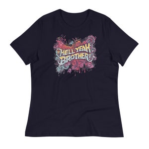 May include: Navy blue t-shirt featuring the phrase "HELL YEAH BROTHER!" in a colorful, graffiti-style design. The graphic includes shades of pink, yellow, blue, and orange, with a dripping effect. A casual, relaxed fit tee.