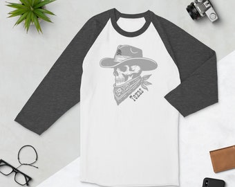 Op de afbeelding: Wit en donkergrijs baseballshirt met een schedel met een cowboyhoed en bandana. Op de bandana staat het woord "Texas". Het shirt heeft donkergrijze mouwen en een witte body.