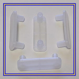 May include: Four clear plastic furniture clips. Three are rectangular with two protruding tabs, and one has a central post. The fourth clip is rectangular with two tabs and a rounded edge. All are white.