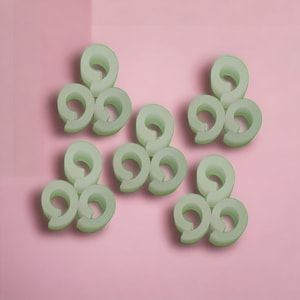 May include: Six sets of three green plastic rings, each set arranged in a triangular shape.