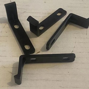 May include: Four black metal brackets with a right angle bend. The brackets are designed to be mounted to a wall or other surface.