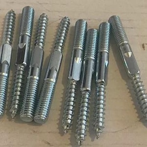 Op de afbeelding: Een close-up van acht zilveren metalen schroeven met een schroefdraad en een platte kop. De schroeven hebben een vierkante inkeping in de kop.