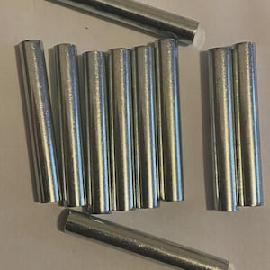 Pode incluir: Um conjunto de varetas de metal prateado. As varetas cilíndricas parecem ser feitas de um material metálico brilhante. Estão dispostas num padrão disperso sobre um fundo neutro. As varetas são provavelmente usadas para construção ou artesanato.