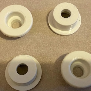 Può includere: Quattro occhielli in plastica bianca con un foro centrale. Gli occhielli sono progettati per essere utilizzati con tessuto o altri materiali.